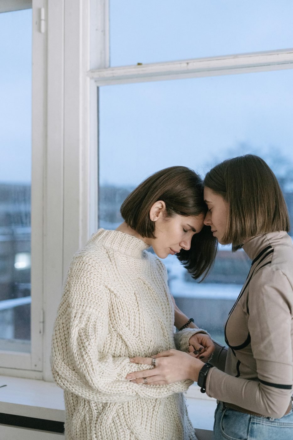 Two people leaning in, forehead to forehead, in quiet support.